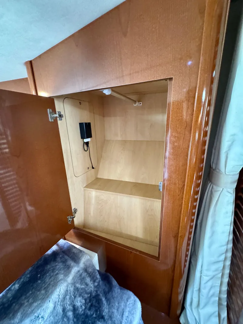 Slide: The Image of 2009 Sea Ray 350 Sundancer cabin storage with open wooden cabinet and shelves. - 21