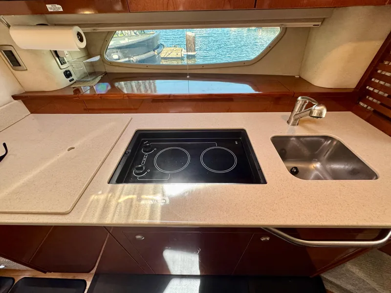 Slide: The Image of 2009 Sea Ray 350 Sundancer yacht kitchen with stove, sink, and window view. - 24