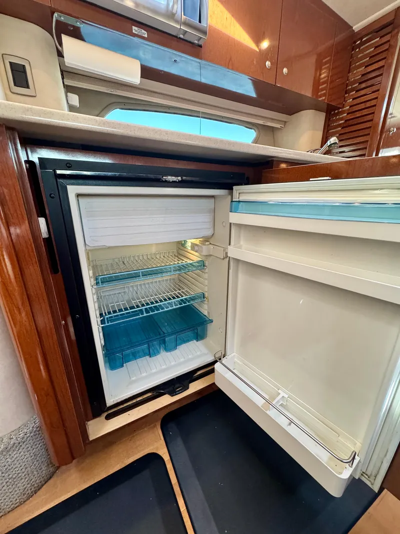 Slide: The Image of 2009 Sea Ray 350 Sundancer interior with open refrigerator, showcasing modern kitchen amenities. - 25