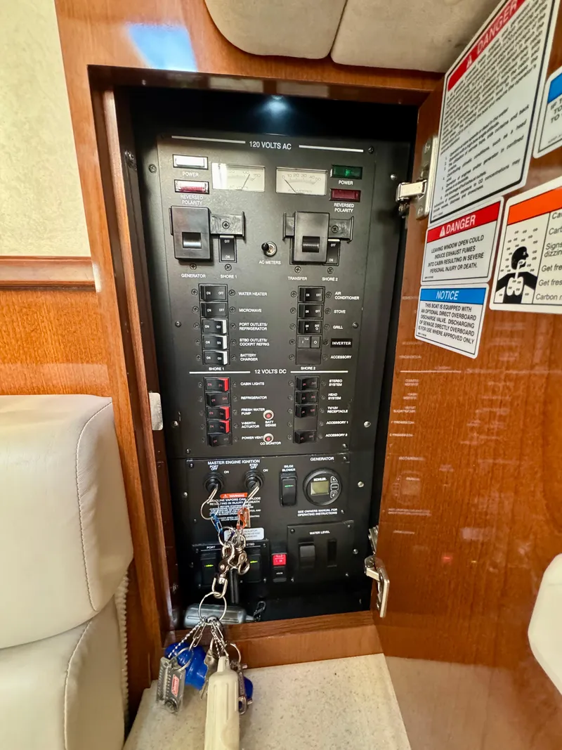 Slide: The Image of Electrical panel inside 2009 Sea Ray 350 Sundancer boat, featuring switches and safety labels. - 32