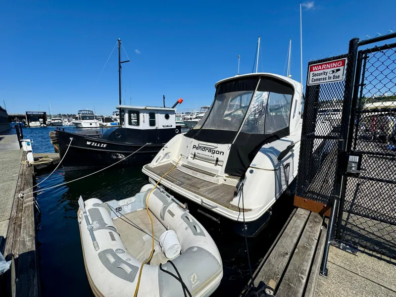 Slide: The Image of 2009 Sea Ray 350 Sundancer docked with inflatable boat nearby, sunny marina setting. - 4