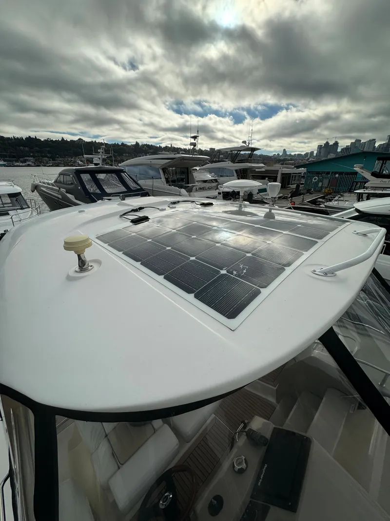 Slide: The Image of 2009 Sea Ray 350 Sundancer with solar panels on deck, docked under cloudy skies. - 8