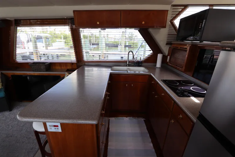 Slide: The Image of 2001 Navigator 4800 CLASSIC yacht kitchen with wooden cabinets, countertop, stove, and sink. - 23