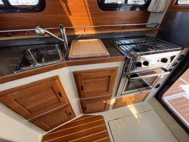 Slide: The Image of 2020 Ranger Tugs R-31 CB kitchen with stove, sink, and wooden cabinetry. - 12