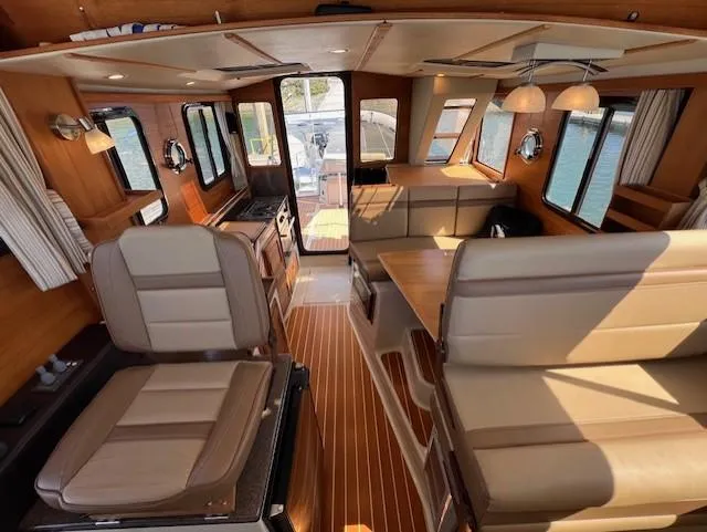 Slide: The Image of Interior of 2020 Ranger Tugs R-31 CB, featuring elegant seating and wood finishes. - 13
