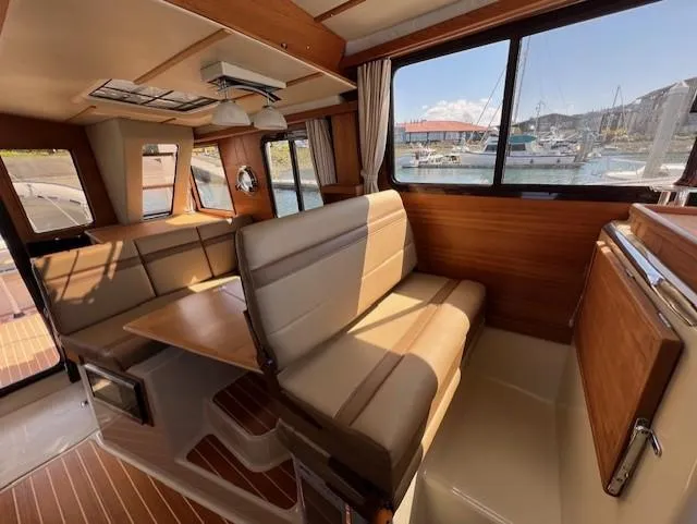 Slide: The Image of 2020 Ranger Tugs R-31 CB interior with seating, table, and marina view. - 9