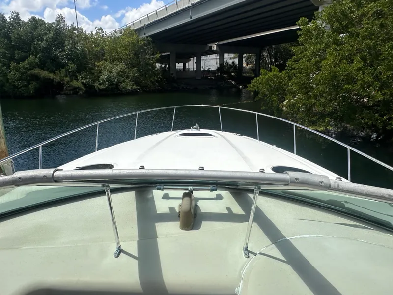 Slide: The Image of 2004 Sea Ray 340 Sundancer boat navigating under a bridge on a sunny day. - 10