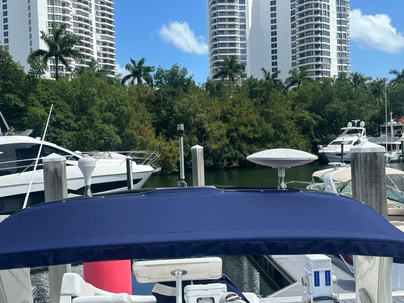 Slide: The Image of 2004 Sea Ray 340 Sundancer docked with high-rise buildings and lush greenery in the background. - 26