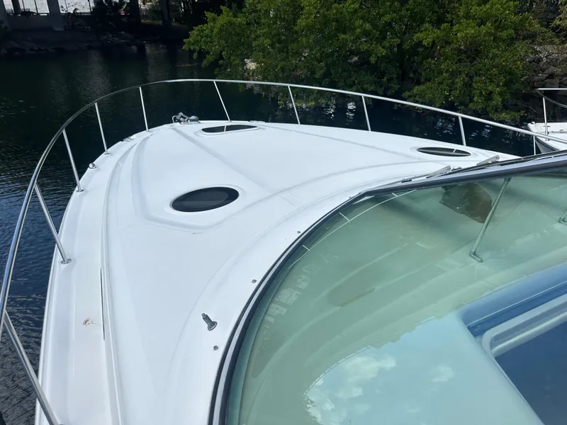 Slide: The Image of 2004 Sea Ray 340 Sundancer boat deck with railing, docked near lush greenery. - 7