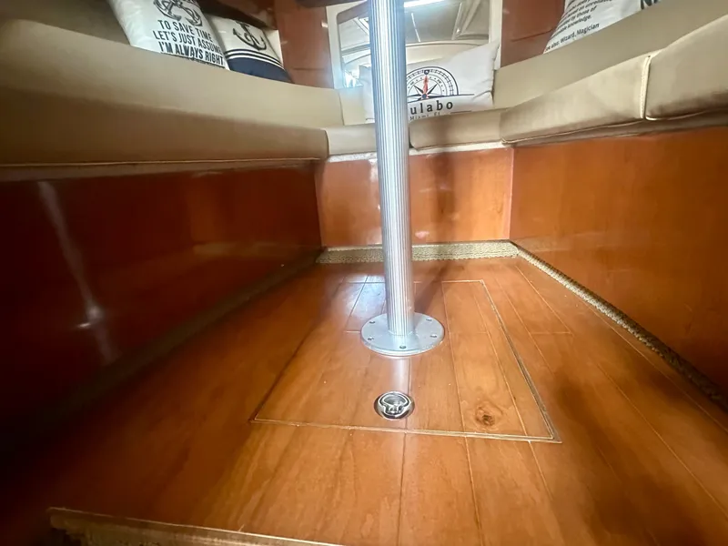 Slide: The Image of Interior of 2012 Sea Ray 310 Sundancer with polished wood flooring and cushioned seating. - 44
