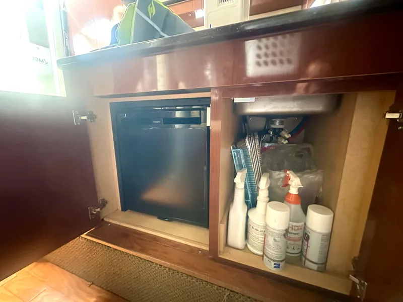 Slide: The Image of 2012 Sea Ray 310 Sundancer cabinet with cleaning supplies and mini fridge. - 45