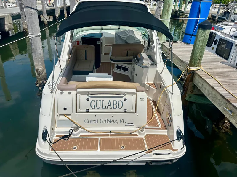 Slide: The Image of 2012 Sea Ray 310 Sundancer docked, featuring a black canopy and wooden deck. - 8