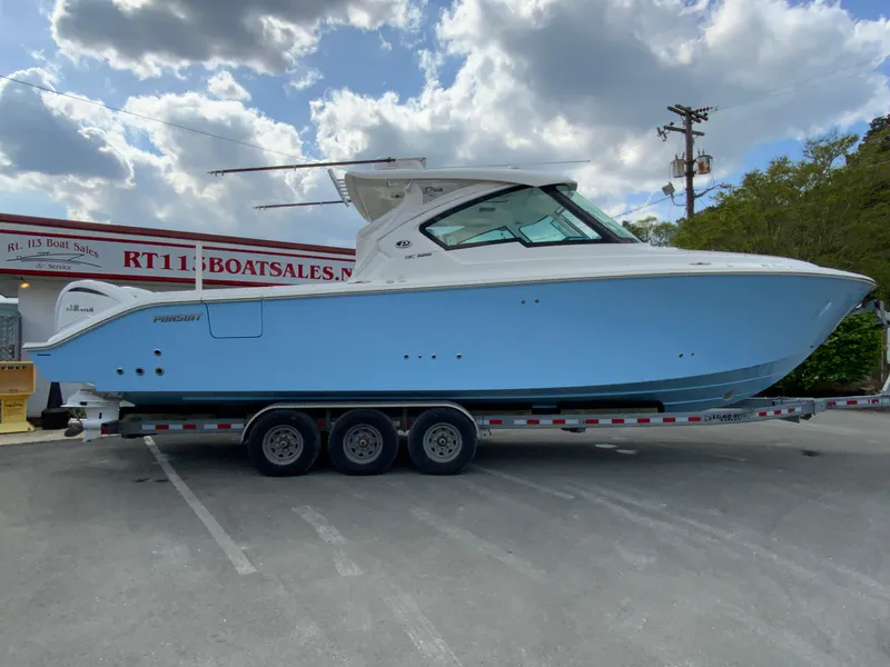 Slide: The Image of 2023 Pursuit DC 326 Dual Console boat on trailer under cloudy sky. - 1