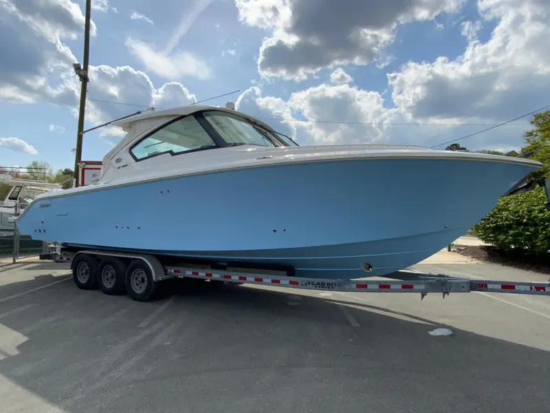 Slide: The Image of 2023 Pursuit DC 326 Dual Console boat on trailer under cloudy sky. - 2