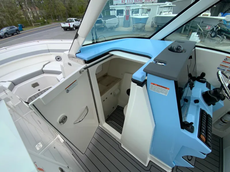 Slide: The Image of 2023 Pursuit DC 326 Dual Console boat interior with helm and open cabin door. - 26