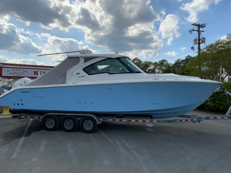 Slide: The Image of 2023 Pursuit DC 326 Dual Console boat on trailer under cloudy sky. - 35