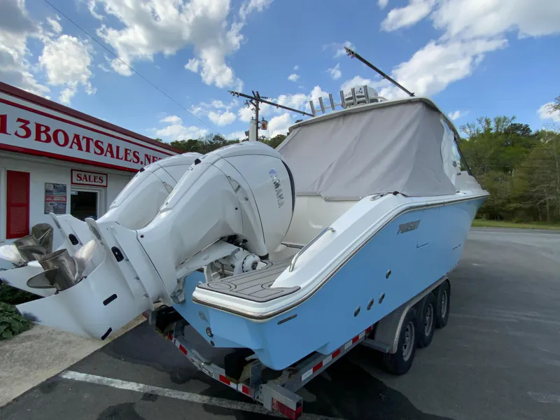 Slide: The Image of 2023 Pursuit DC 326 Dual Console boat on trailer, parked near a boat sales shop. - 36
