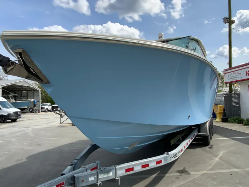 Slide: The Image of 2023 Pursuit DC 326 Dual Console boat on trailer, light blue hull, outdoor setting. - 4