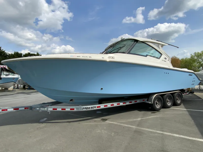 Slide: The Image of 2023 Pursuit DC 326 Dual Console boat on a trailer under a cloudy sky. - 5