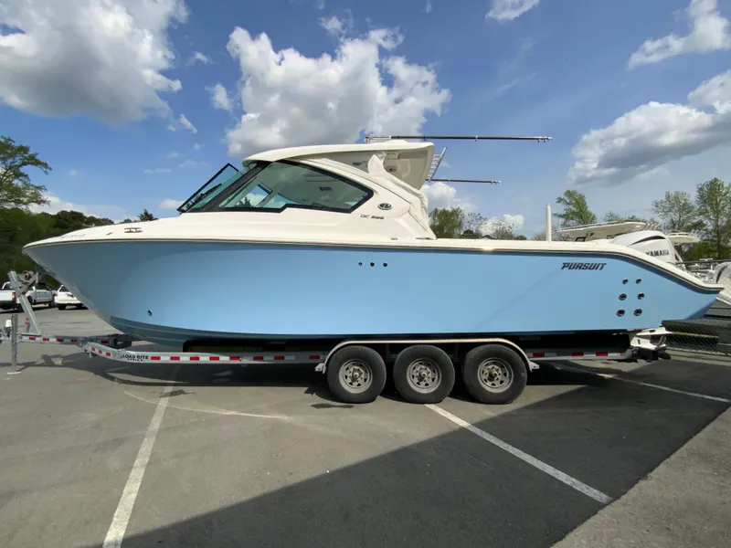 Slide: The Image of 2023 Pursuit DC 326 Dual Console boat on a trailer under a partly cloudy sky. - 6