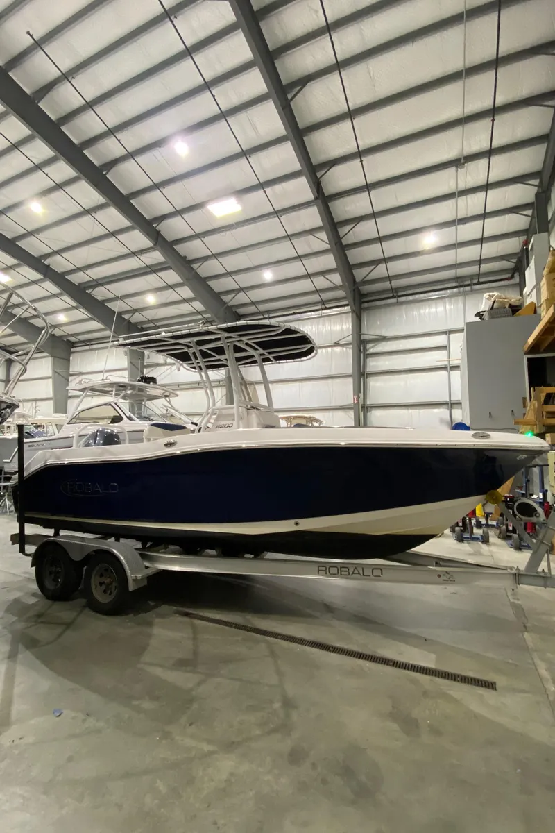 Slide: The Image of 2022 Robalo R200 Center Console boat on trailer in a spacious indoor storage facility. - 1