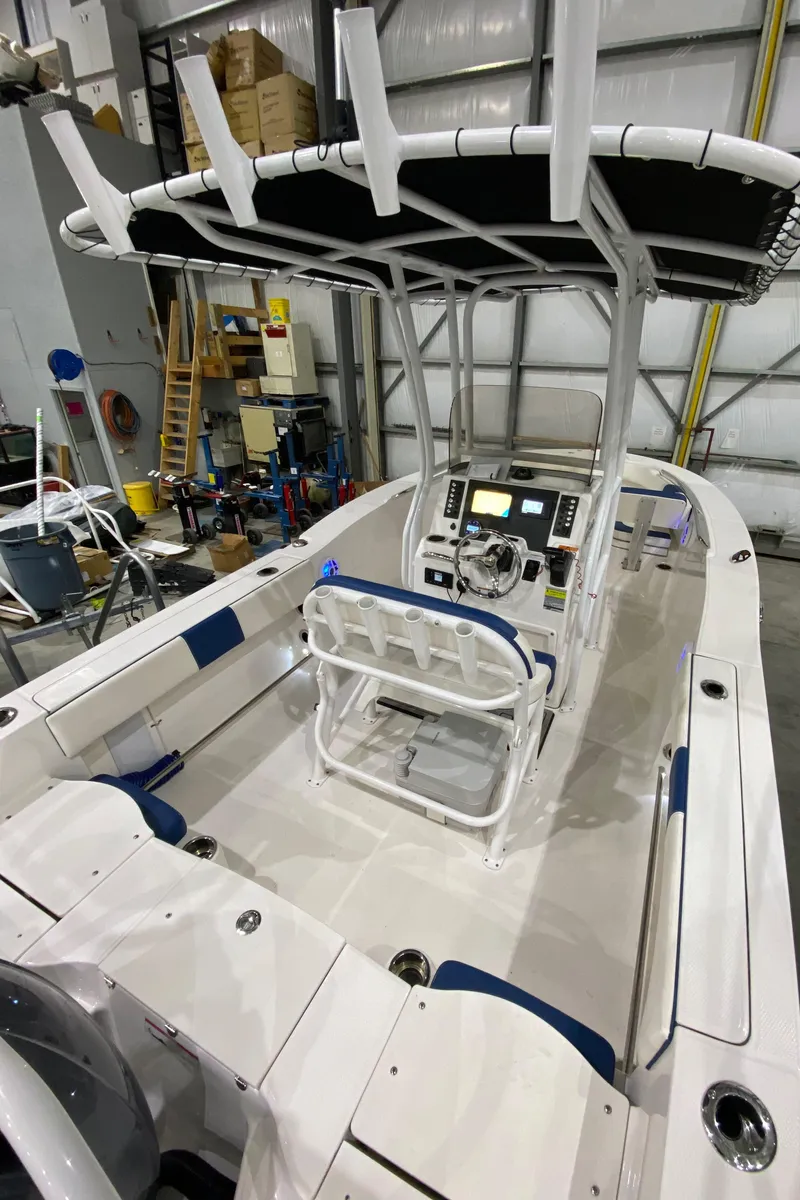 Slide: The Image of 2022 Robalo R200 Center Console boat in a garage, showcasing helm and seating area. - 10