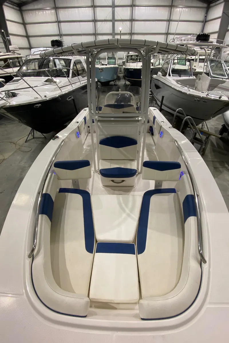 Slide: The Image of 2022 Robalo R200 Center Console boat with blue and white seating in a showroom. - 20