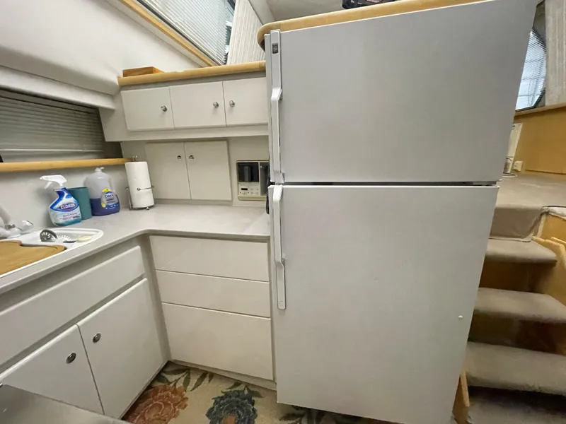 Slide: The Image of 1995 Carver 440 Aft Cabin Motor Yacht kitchen with white cabinets and large refrigerator. - 38
