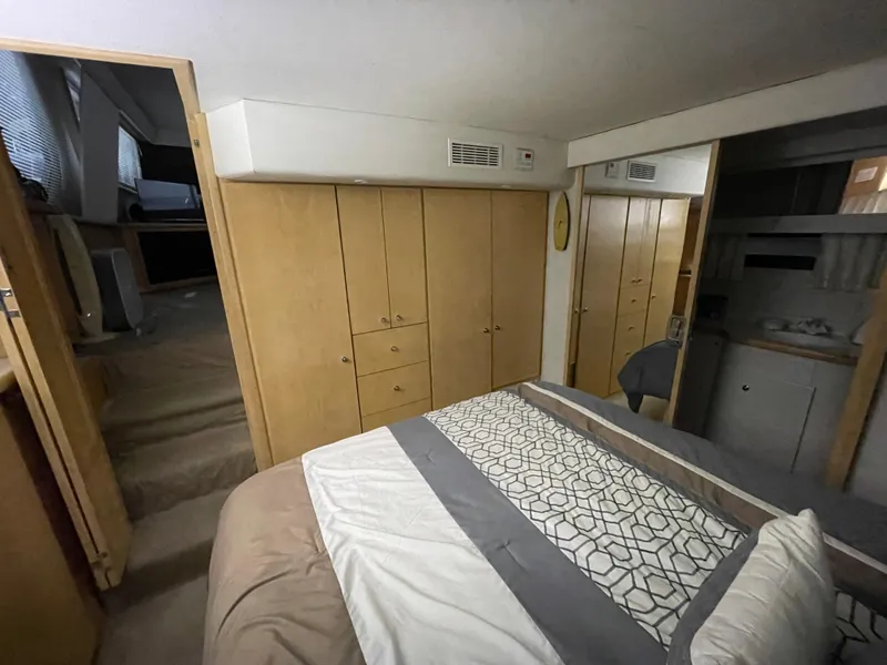 Slide: The Image of 1995 Carver 440 Aft Cabin Motor Yacht bedroom with wooden cabinets and patterned bedding. - 48