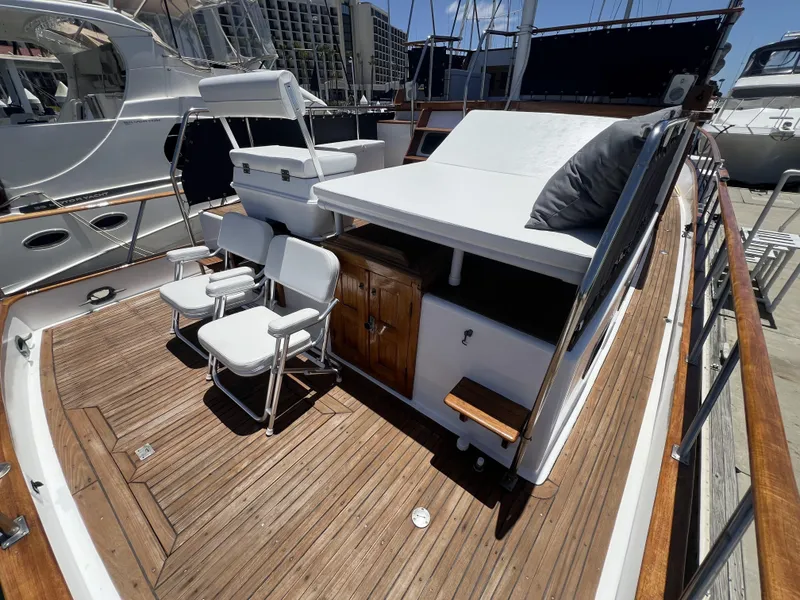 Slide: The Image of 1984 DeFever 41 Trawler with wooden deck and white seating in marina. - 10