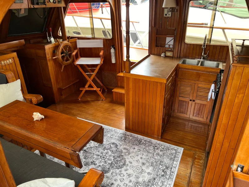 Slide: The Image of 1984 DeFever 41 Trawler interior with wooden furnishings, steering wheel, and kitchenette. - 12