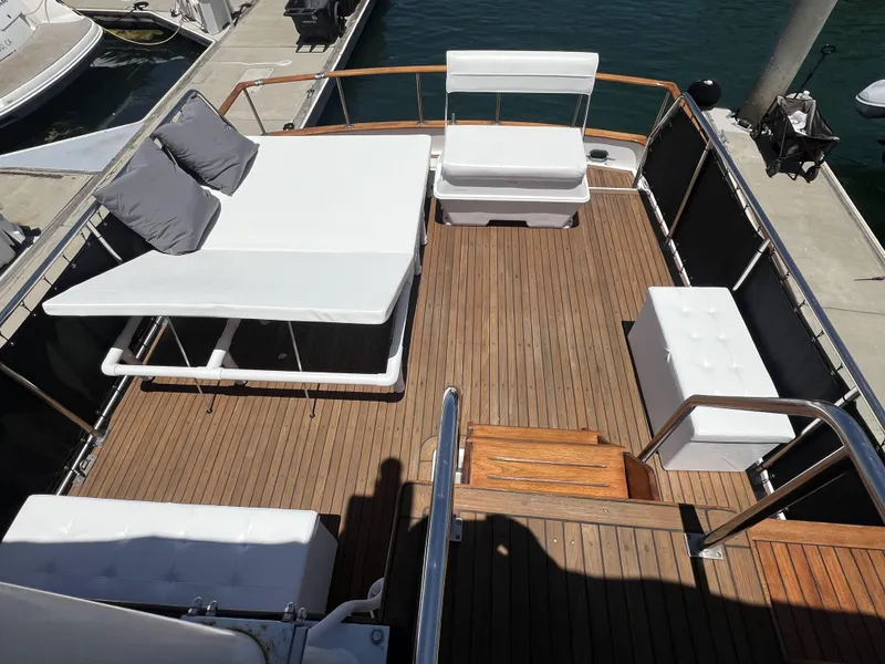 Slide: The Image of 1984 DeFever 41 Trawler deck with white seating, wooden flooring, and docked at marina. - 5