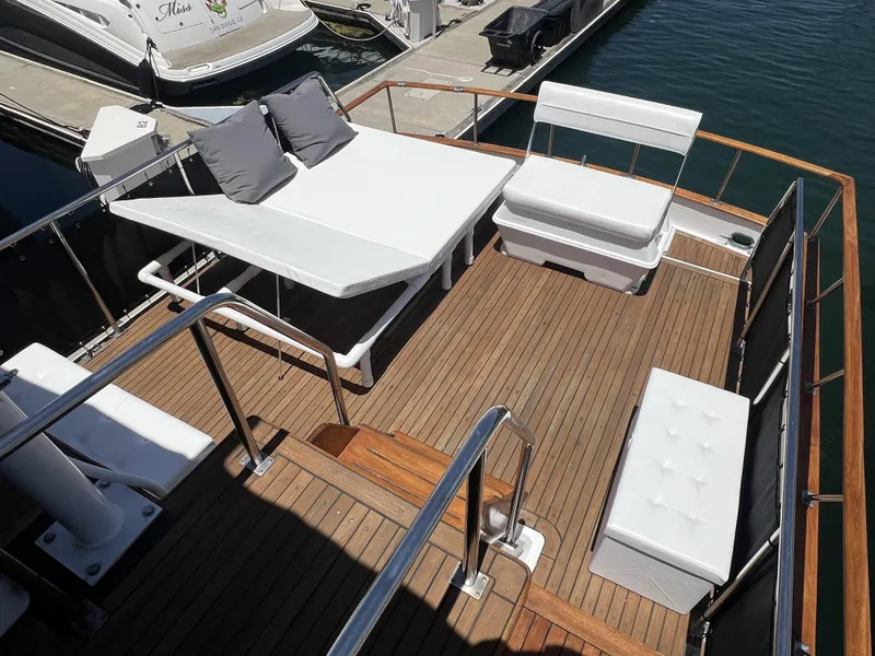 Slide: The Image of 1984 DeFever 41 Trawler deck with white seating and table, docked at marina. - 7