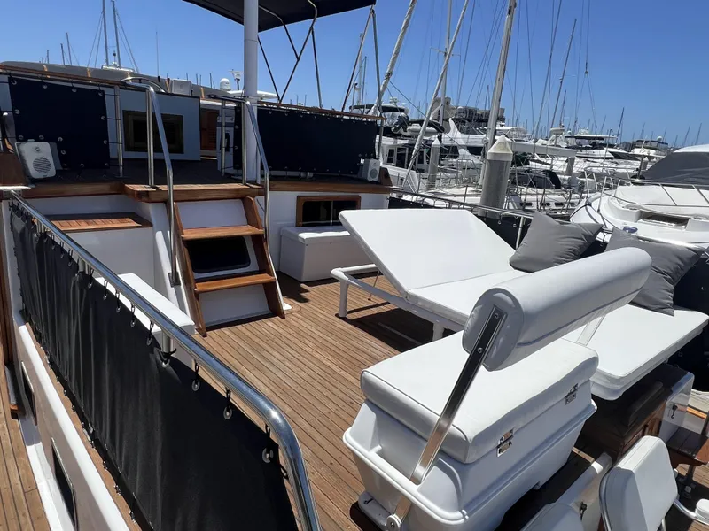 Slide: The Image of 1984 DeFever 41 Trawler with spacious deck, sun loungers, and marina backdrop. - 8