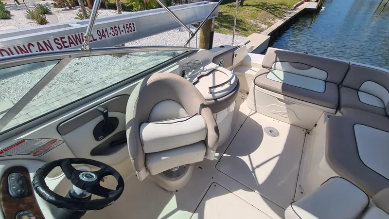 Slide: The Image of 2004 Sea Ray 270 Sundeck interior with seating and steering wheel, docked by water. - 11