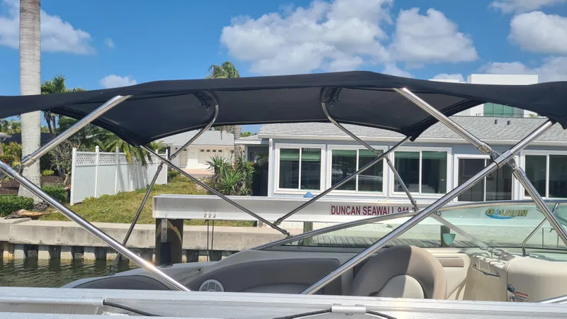 Slide: The Image of 2004 Sea Ray 270 Sundeck boat with canopy, docked near waterfront homes. - 13