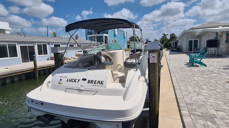Slide: The Image of 2004 Sea Ray 270 Sundeck boat docked by waterfront homes under a blue sky. - 17