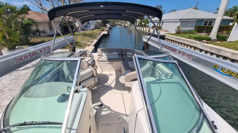 Slide: The Image of 2004 Sea Ray 270 Sundeck boat docked in a canal, featuring spacious seating and canopy. - 6