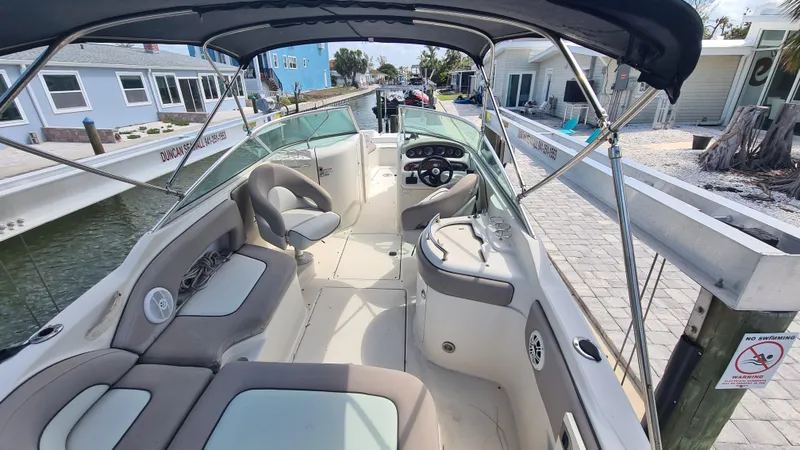 Slide: The Image of 2004 Sea Ray 270 Sundeck boat with spacious seating and canopy, docked near waterfront homes. - 7