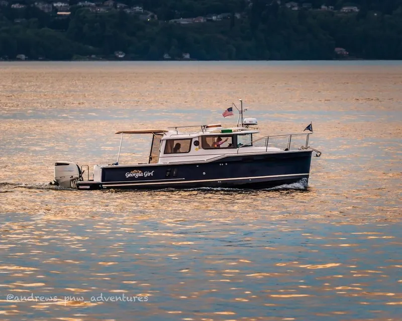 Slide: The Image of 2018 Ranger Tugs R27 OB boat cruising on a serene lake at sunset. - 0