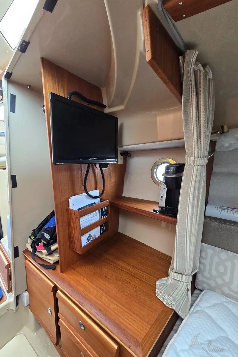 Slide: The Image of 2018 Ranger Tugs R27 OB cabin interior with TV, storage, and cozy sleeping area. - 11