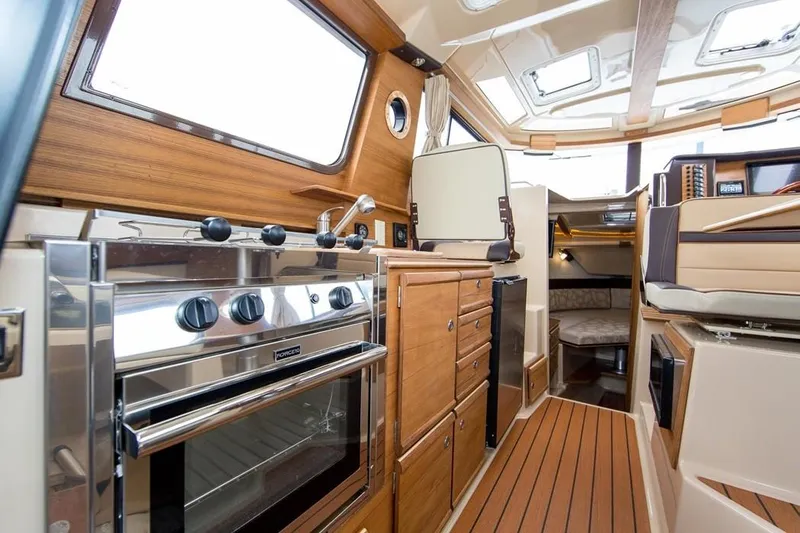 Slide: The Image of 2018 Ranger Tugs R27 OB interior with wood finish, kitchen, and seating area. - 7