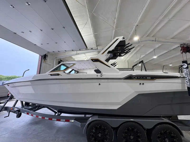 Slide: The Image of 2025 MasterCraft XStar 23 boat on trailer in showroom setting. - 2