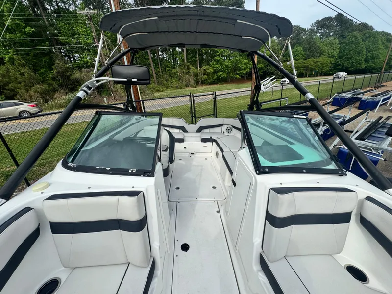 Slide: The Image of 2014 Yamaha Boats 212X interior with dual windshields and seating, parked outdoors. - 10