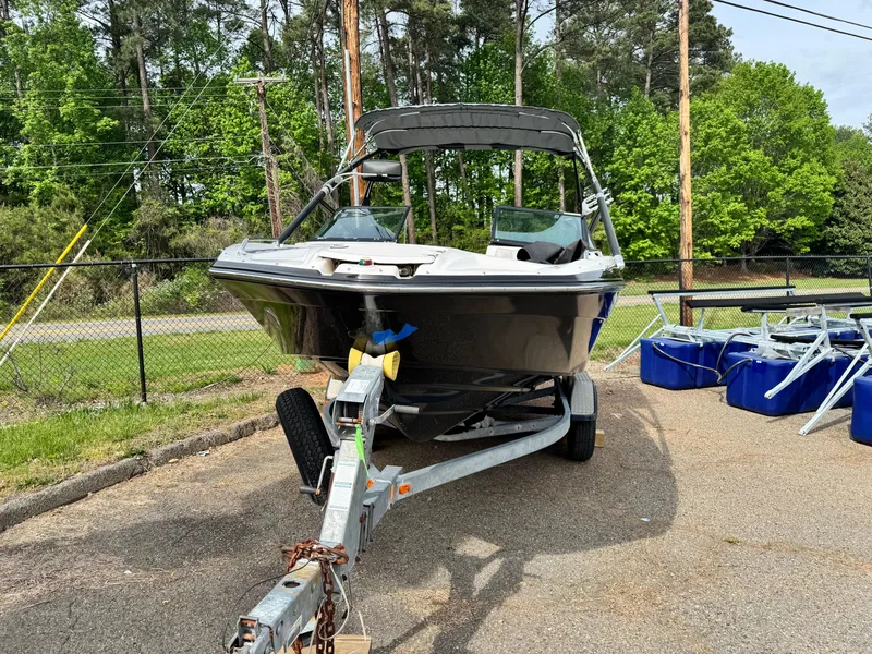 Slide: The Image of 2014 Yamaha Boats 212X on trailer, parked outdoors with trees in background. - 15