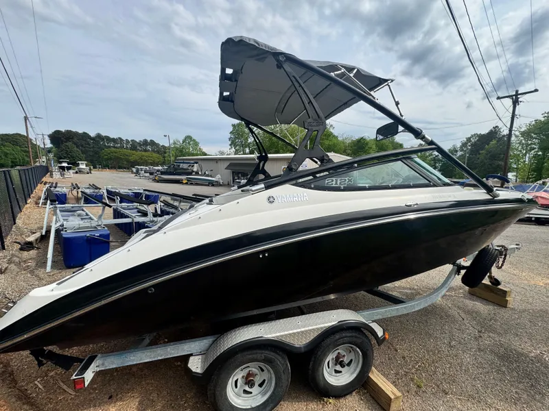 Slide: The Image of 2014 Yamaha Boats 212X on trailer, black and white, with canopy, parked outdoors. - 4