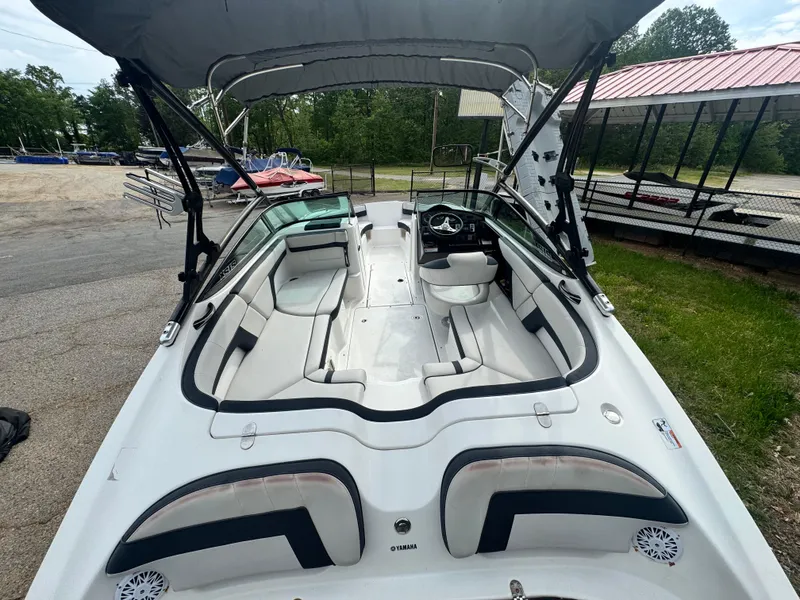 Slide: The Image of 2014 Yamaha Boats 212X with spacious seating and canopy, parked outdoors. - 6