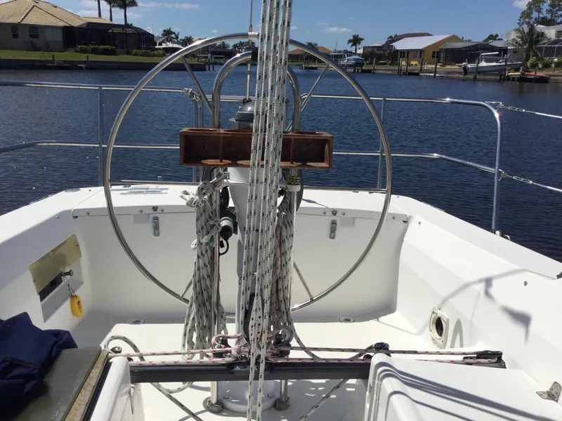 Slide: The Image of 1997 J Boats J/32 sailboat cockpit with steering wheel and ropes, docked by waterfront homes. - 19