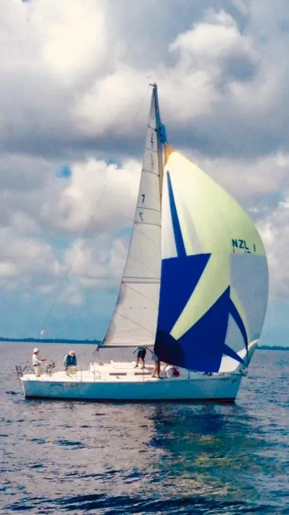 Slide: The Image of 1997 J Boats J/32 sailboat with colorful spinnaker on calm water under cloudy sky. - 2