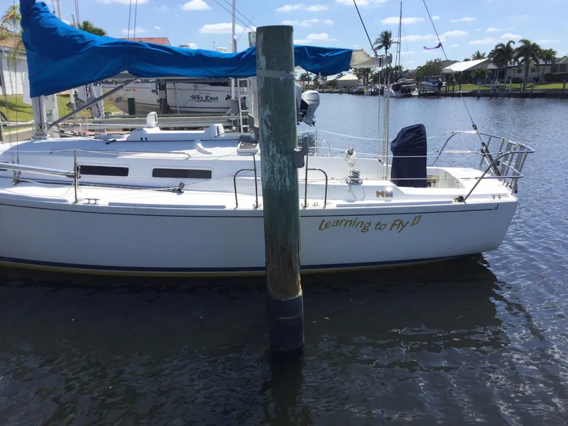 Slide: The Image of 1997 J Boats J/32 sailboat docked, named "Learning to Fly II," with blue cover. - 3